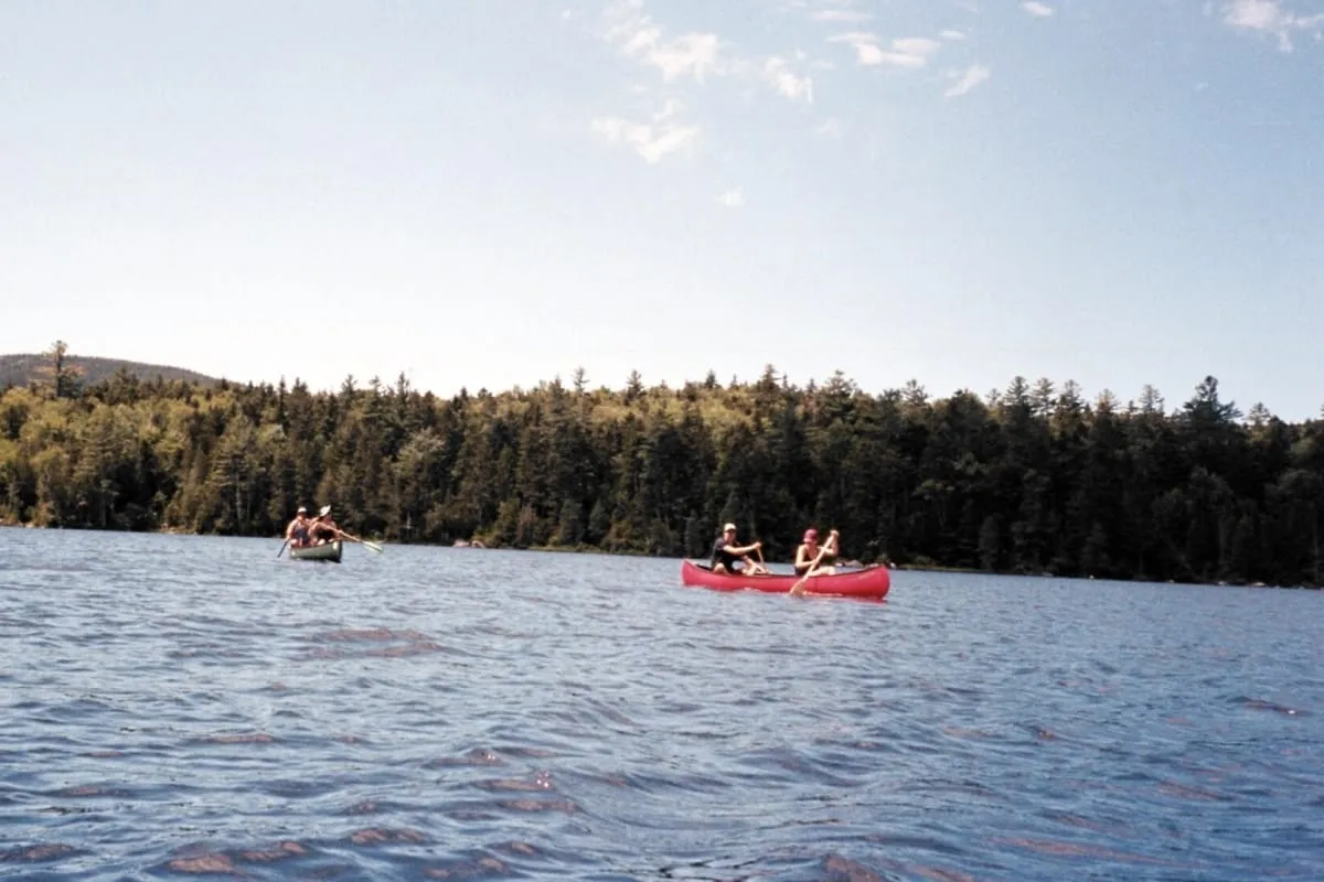 Two red canoes on a blue lake with a forested shoreline